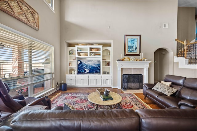 living room with hardwood / wood-style floors, a high ceiling, and a tiled fireplace