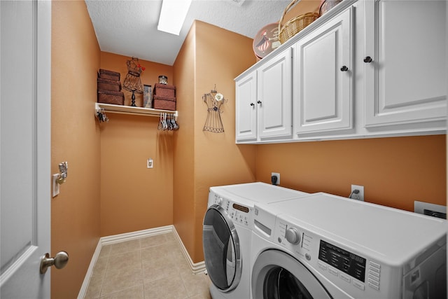 washroom featuring washer and dryer, light tile patterned floors, cabinets, and a textured ceiling