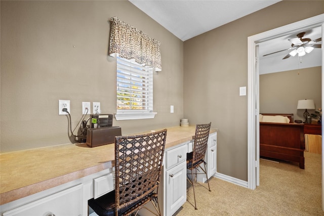 carpeted home office featuring ceiling fan and built in desk