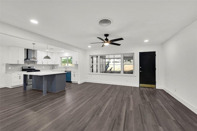 kitchen featuring a center island, dark wood-type flooring, wall chimney exhaust hood, appliances with stainless steel finishes, and white cabinetry