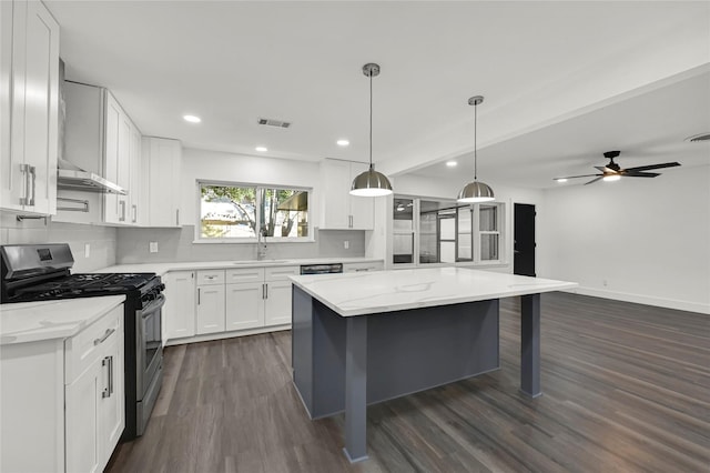 kitchen featuring white cabinets, appliances with stainless steel finishes, light stone countertops, and dark wood-type flooring