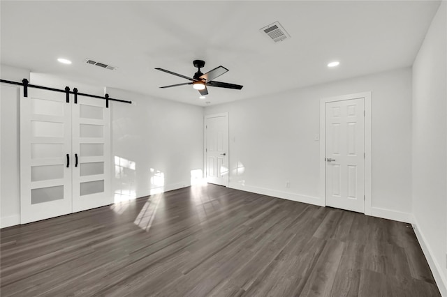 interior space featuring a barn door, ceiling fan, and dark hardwood / wood-style floors