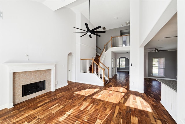 unfurnished living room with dark hardwood / wood-style flooring, a tile fireplace, and high vaulted ceiling