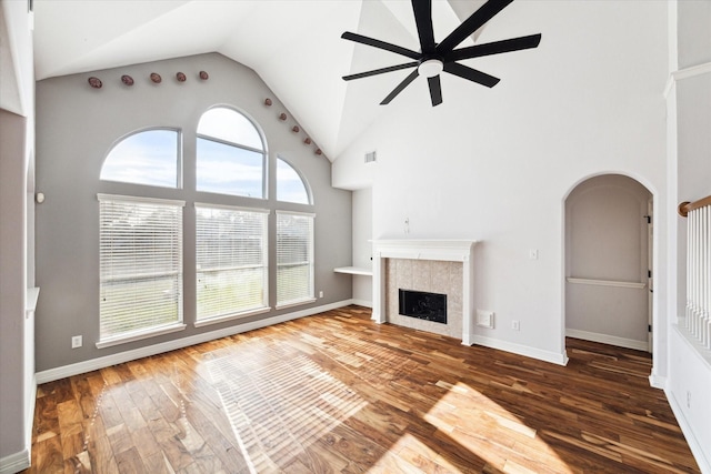 unfurnished living room featuring ceiling fan, a tile fireplace, wood-type flooring, and high vaulted ceiling