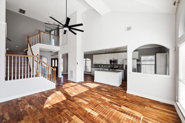 unfurnished living room with hardwood / wood-style flooring, high vaulted ceiling, and a healthy amount of sunlight