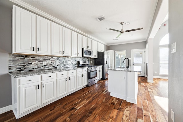 kitchen with white cabinets, appliances with stainless steel finishes, and light stone countertops