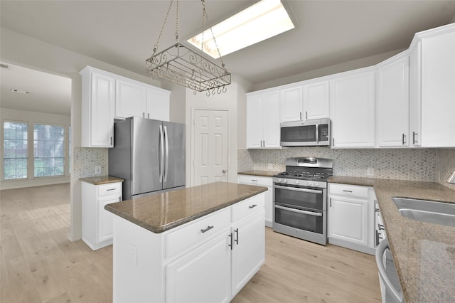 kitchen featuring sink, appliances with stainless steel finishes, white cabinetry, a center island, and decorative backsplash