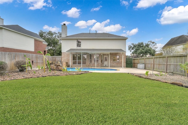 rear view of property with a fenced in pool, a patio area, and a lawn