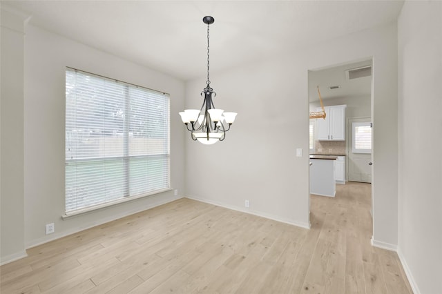 unfurnished dining area with light hardwood / wood-style flooring and a notable chandelier