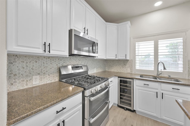 kitchen with wine cooler, sink, dark stone counters, stainless steel appliances, and white cabinets