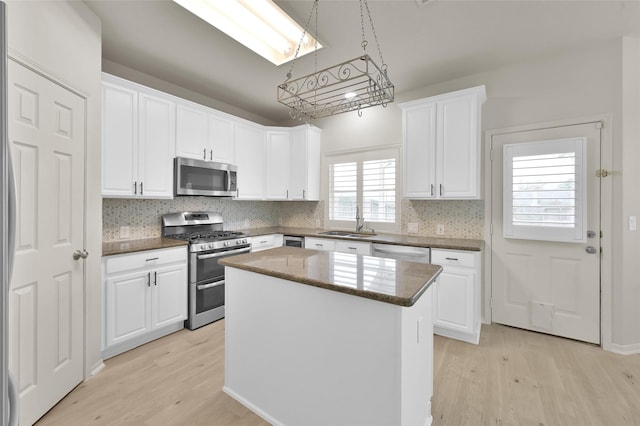 kitchen with sink, appliances with stainless steel finishes, a center island, white cabinets, and light wood-type flooring