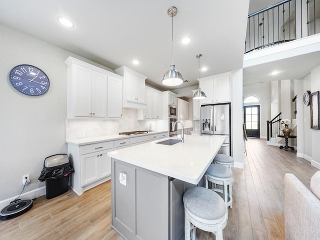 kitchen featuring white cabinets, light wood-type flooring, hanging light fixtures, and sink