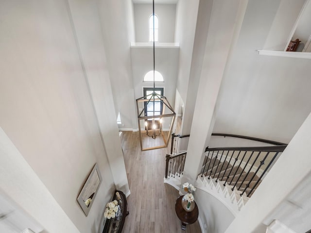 stairway with wood-type flooring and a towering ceiling