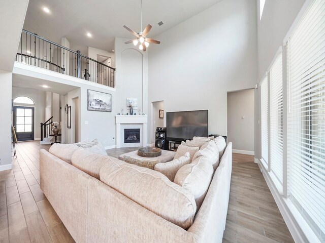 living room featuring a high ceiling, light hardwood / wood-style floors, and ceiling fan