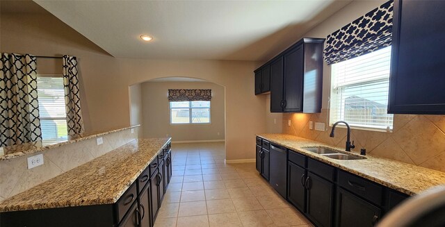 kitchen featuring light stone countertops, dishwasher, tasteful backsplash, and sink