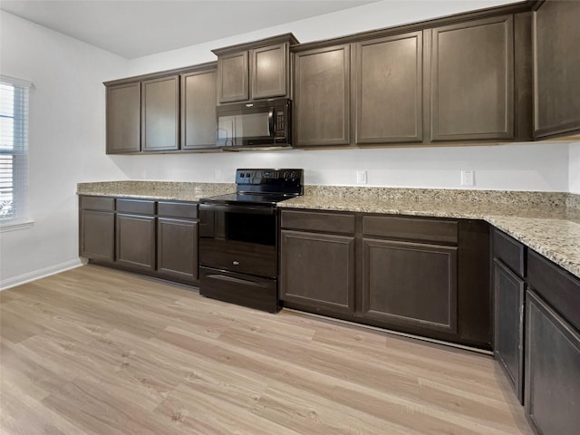 kitchen with black appliances, light stone counters, dark brown cabinetry, and light hardwood / wood-style flooring