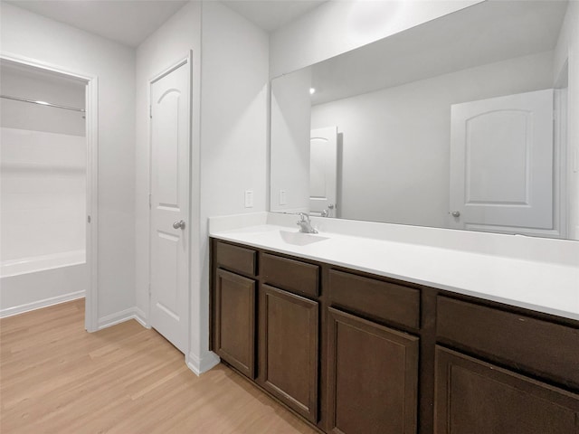 bathroom with wood-type flooring, vanity, and  shower combination