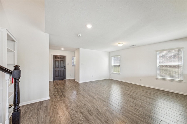 unfurnished living room featuring dark hardwood / wood-style flooring and a textured ceiling