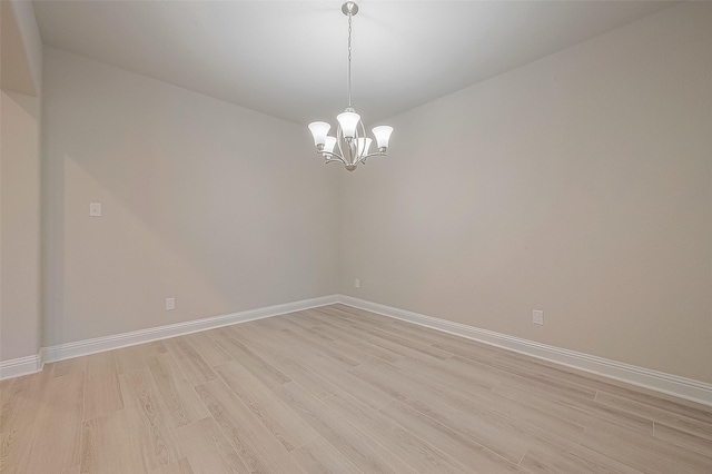 unfurnished room with light hardwood / wood-style floors and a notable chandelier