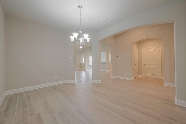 spare room featuring a chandelier and light hardwood / wood-style floors