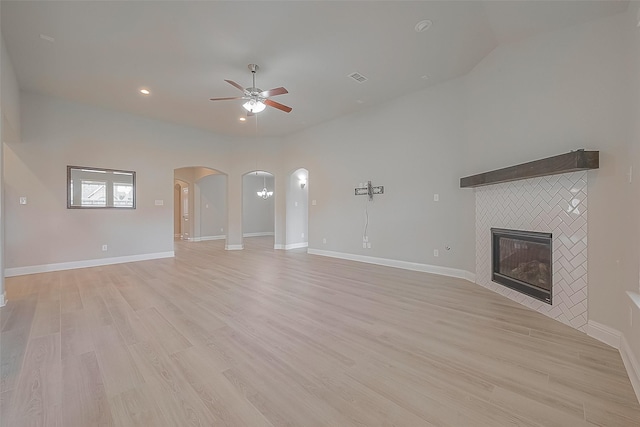 unfurnished living room with ceiling fan, a fireplace, and light hardwood / wood-style floors