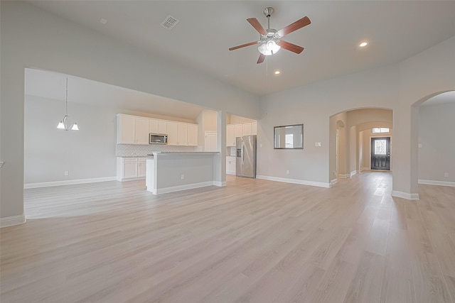 unfurnished living room featuring light hardwood / wood-style flooring and ceiling fan with notable chandelier