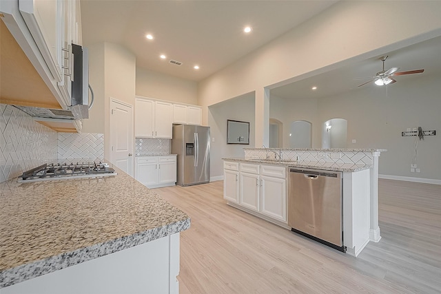 kitchen with a kitchen island, white cabinets, light wood-type flooring, and appliances with stainless steel finishes