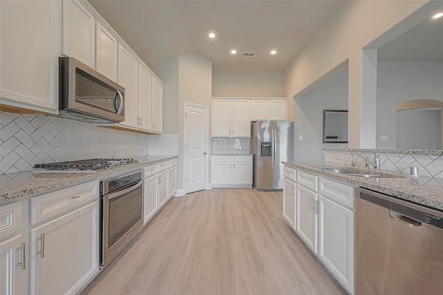 kitchen featuring appliances with stainless steel finishes, light hardwood / wood-style floors, white cabinetry, and sink