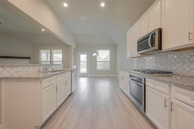 kitchen with white cabinets, stainless steel appliances, and vaulted ceiling