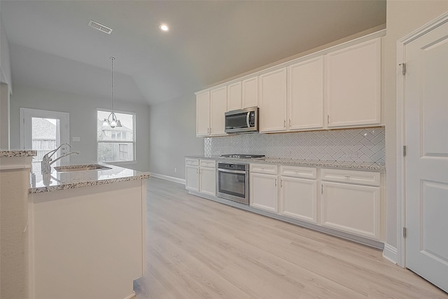 kitchen featuring lofted ceiling, hanging light fixtures, appliances with stainless steel finishes, light hardwood / wood-style floors, and white cabinetry