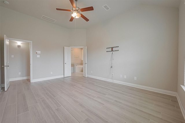 empty room with ceiling fan, high vaulted ceiling, and light wood-type flooring