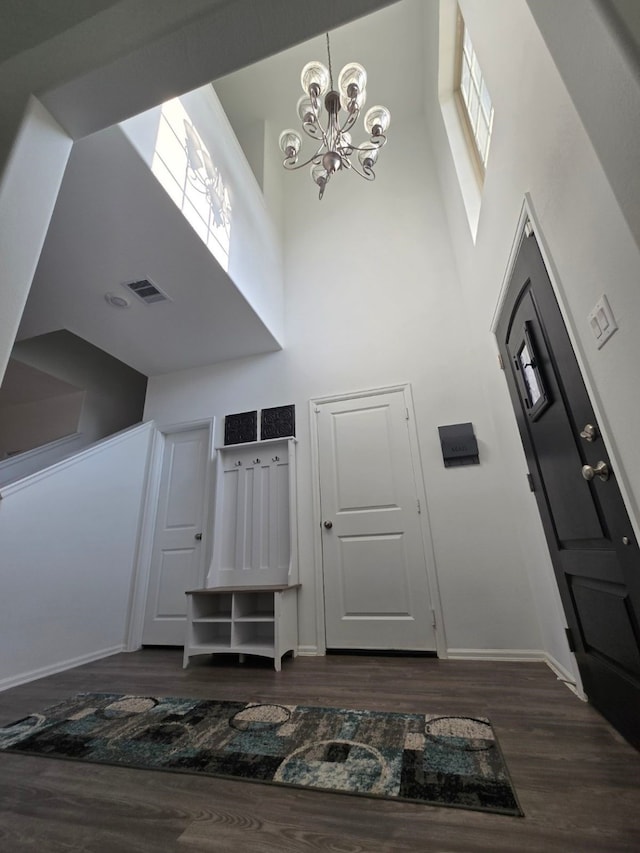 entrance foyer featuring a notable chandelier, a healthy amount of sunlight, dark hardwood / wood-style flooring, and a high ceiling