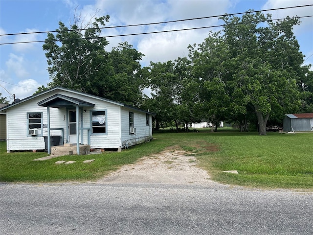 view of front facade with a storage unit, cooling unit, and a front yard