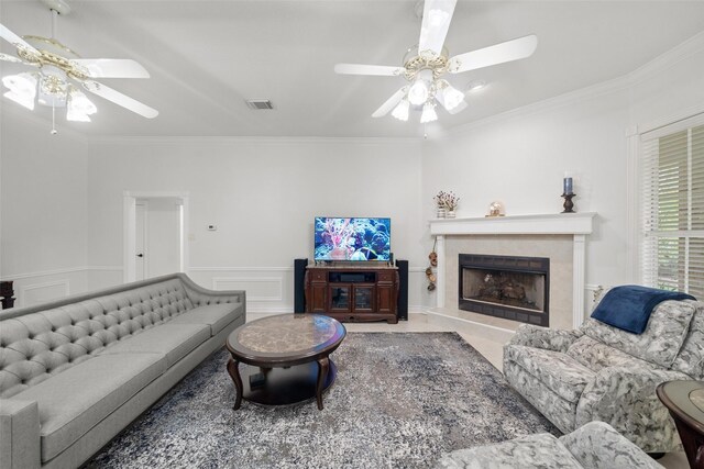 living room with a tile fireplace, crown molding, and ceiling fan