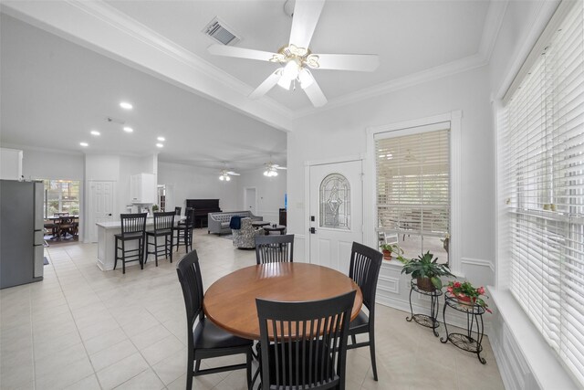 dining area featuring ceiling fan, light tile patterned flooring, and crown molding