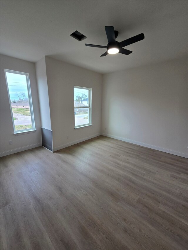 empty room with ceiling fan, plenty of natural light, and light hardwood / wood-style floors