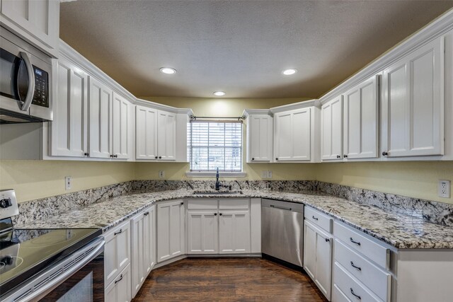 kitchen with dark wood-type flooring, sink, a textured ceiling, white cabinetry, and stainless steel appliances