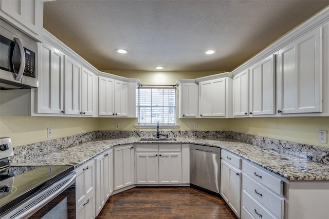 kitchen with sink, stainless steel appliances, dark hardwood / wood-style flooring, white cabinets, and light stone countertops