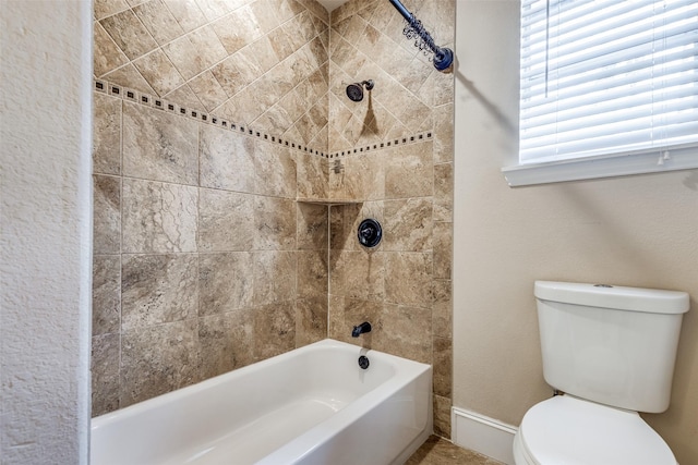 bathroom with tiled shower / bath combo and toilet