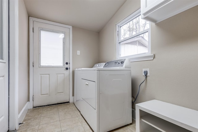 clothes washing area featuring washing machine and dryer, light tile patterned flooring, and cabinets