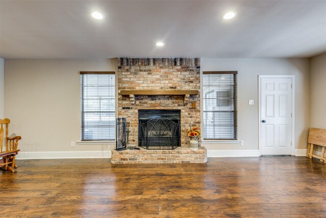 living room with dark hardwood / wood-style flooring and a brick fireplace