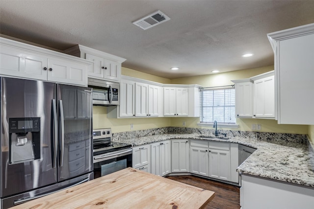 kitchen with sink, a textured ceiling, stainless steel appliances, white cabinets, and light stone countertops