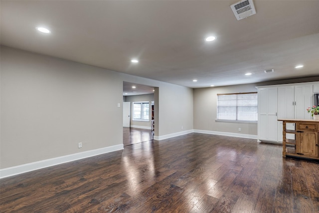 unfurnished living room with dark wood-type flooring and a healthy amount of sunlight