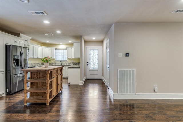 kitchen featuring sink, stainless steel refrigerator with ice dispenser, dark hardwood / wood-style floors, a kitchen island, and white cabinetry