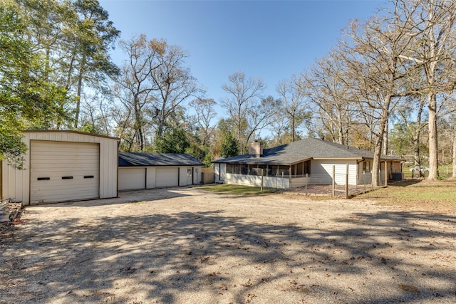 exterior space featuring a garage, an outdoor structure, and a sunroom