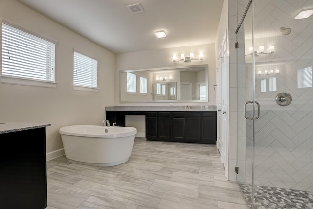 bathroom featuring vanity and independent shower and bath