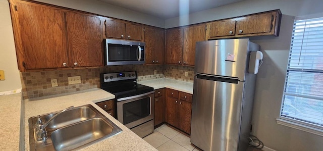 kitchen featuring decorative backsplash, light tile patterned floors, stainless steel appliances, and sink