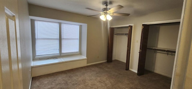 unfurnished bedroom with ceiling fan, two closets, and dark colored carpet