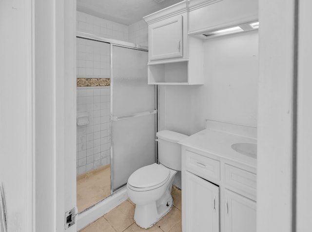 bathroom featuring tile patterned flooring, vanity, a shower with shower door, and toilet