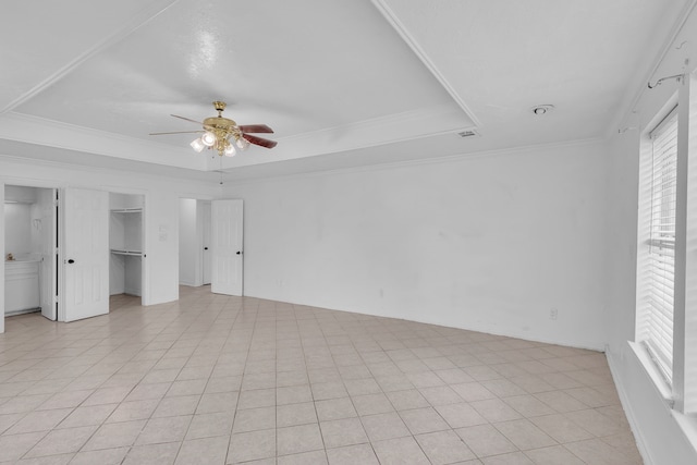 unfurnished bedroom featuring light tile patterned floors, a raised ceiling, ceiling fan, and crown molding